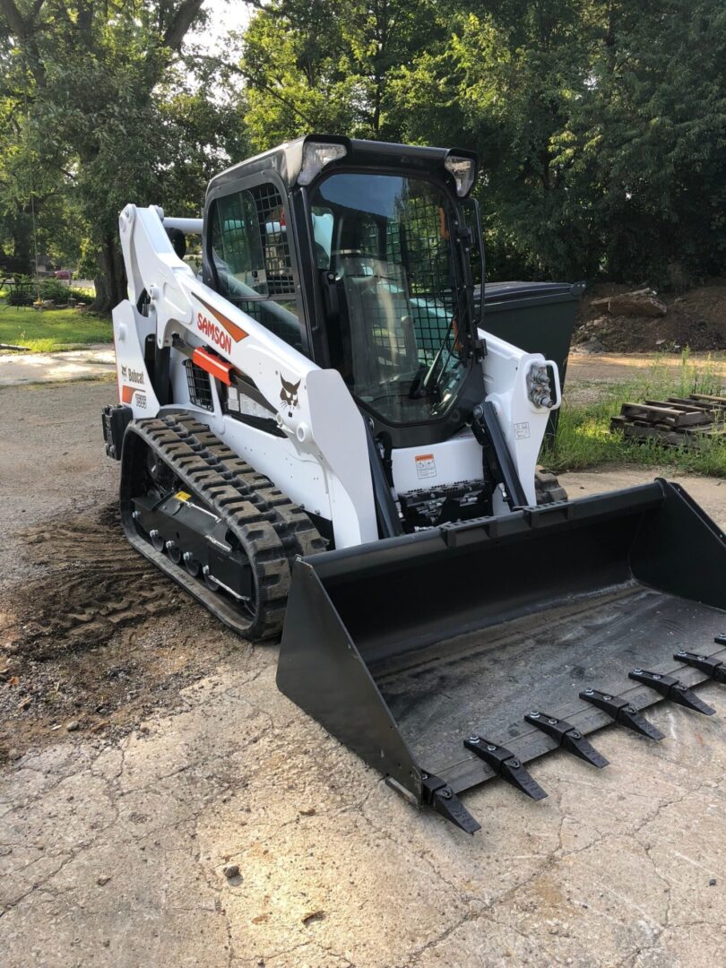 A bobcat with its front bucket up on the ground.