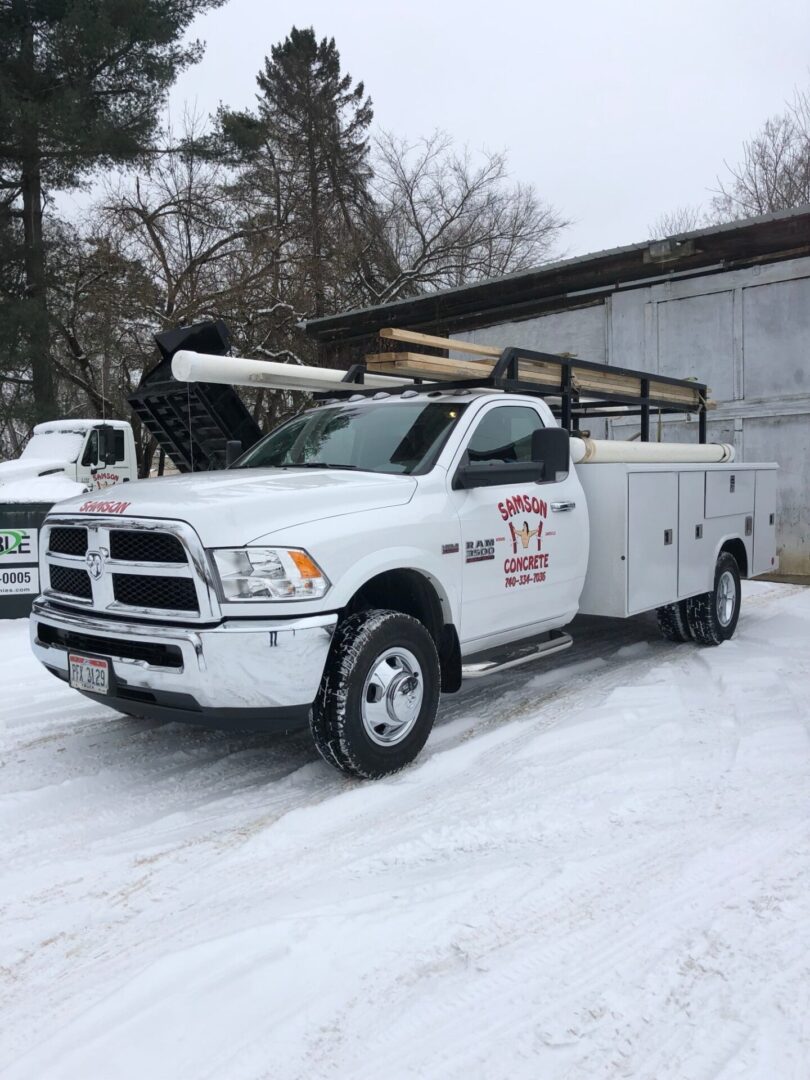 A white truck parked in the snow with other trucks.