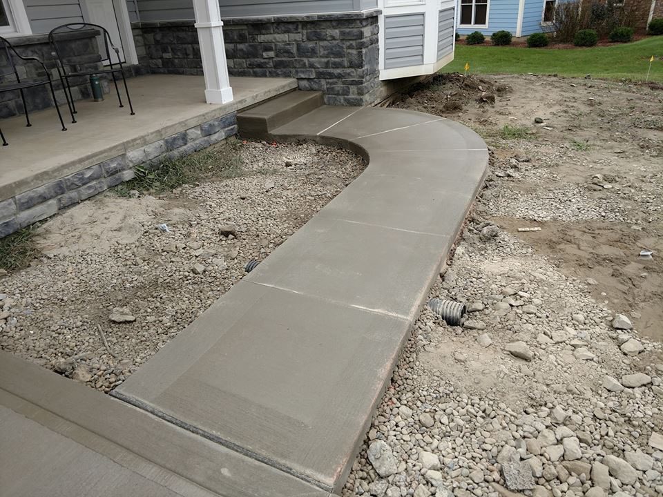 A concrete walkway is being built on the side of a house.
